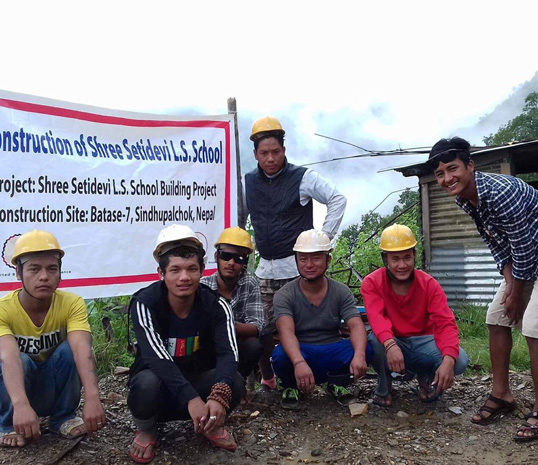 Equipe des ouvriers népalais devant la banderole de la reconstruction